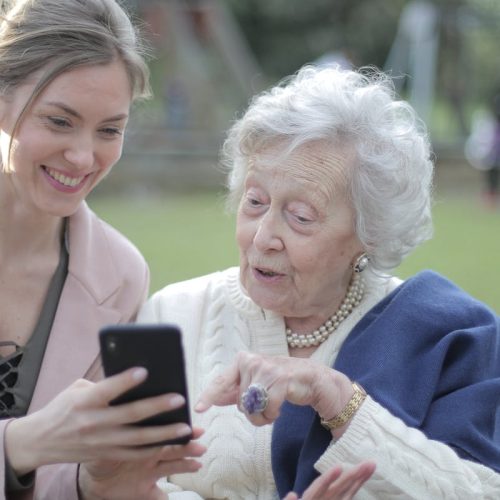 pexels-photo-3791664-3791664 senioren mevrouw die iphone hul;p krijgt en blij wordt van iets nieuws leren