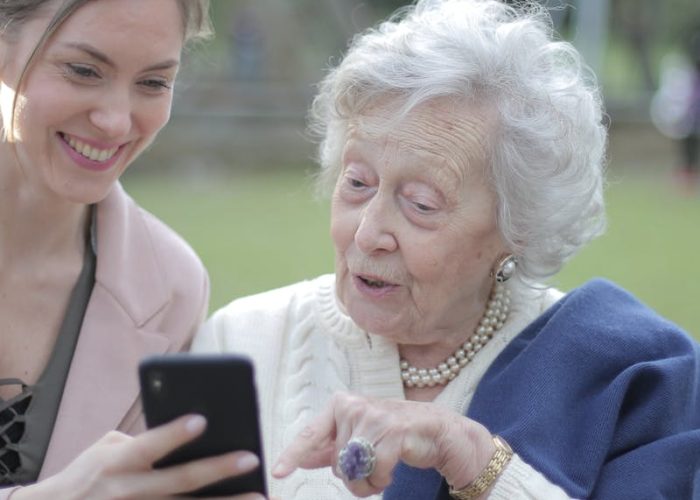 senioren mevrouw die iphone hul;p krijgt en blij wordt van iets nieuws leren