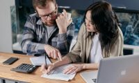 pexels-photo-6964107-6964107 A couple analyzing financial documents with calculator and laptop on a table.